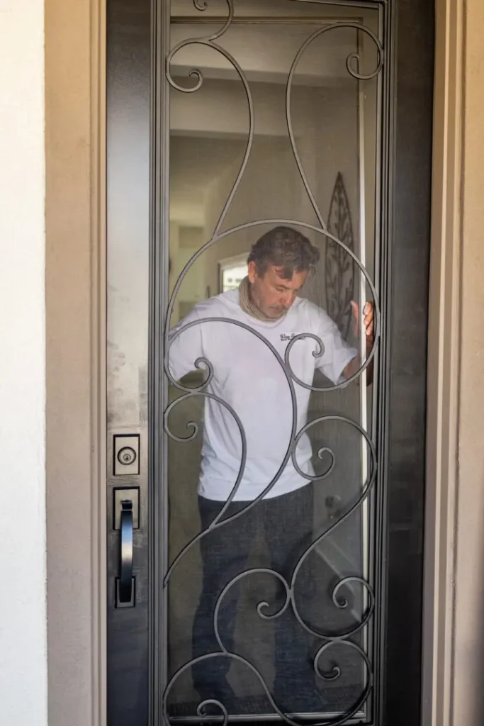 A man standing in front of a wrought iron door.