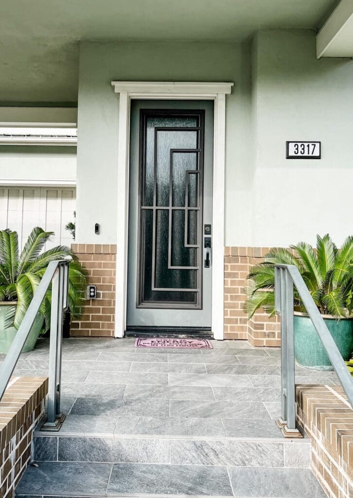 The front door of a home with plants on the steps.